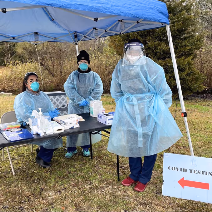 Healthcare professional administering a vaccine to a woman with a young girl watching.