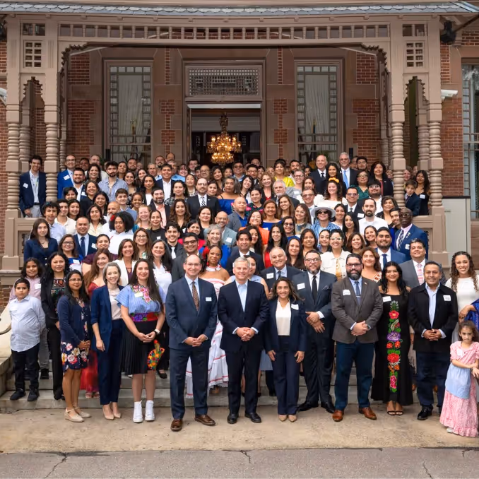 Three women closely examining and discussing architectural drawings pinned on a wall, with one pointing and another taking notes.