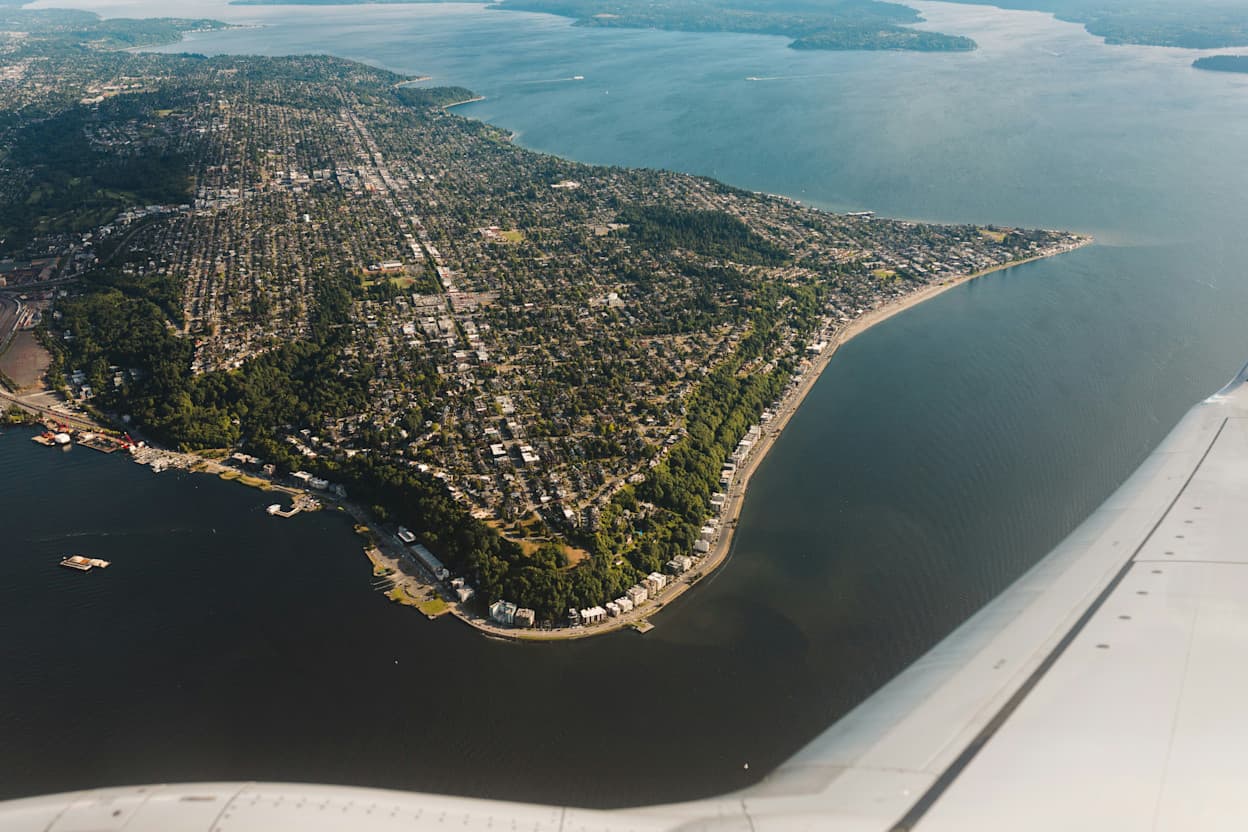 Taken from a plane-window, the peninsula of West Seattle is captured within the surrounding water. Lined with trees and houses, you can almost decipher the street patterns in the neighborhood among the greenery.