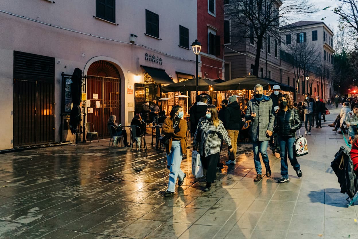 People walking on a cobblestone road in the rain in Pigneto, Rome. 