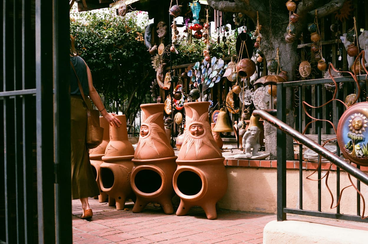 An image of terracotta planters and other items derived from Mexican culture, such as windchimes, in the front of a retail store or gift shop in the Old Town neighborhood of San Diego.