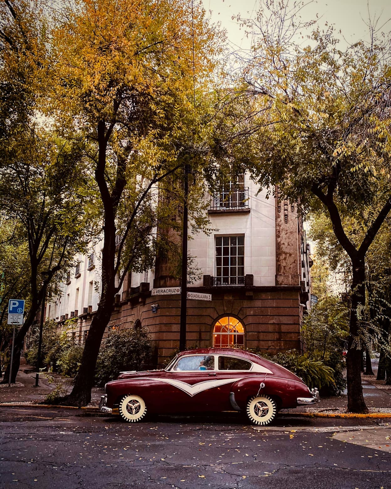A vintage car parked on a corner on a tree-lined street in Condesa, Mexico City
