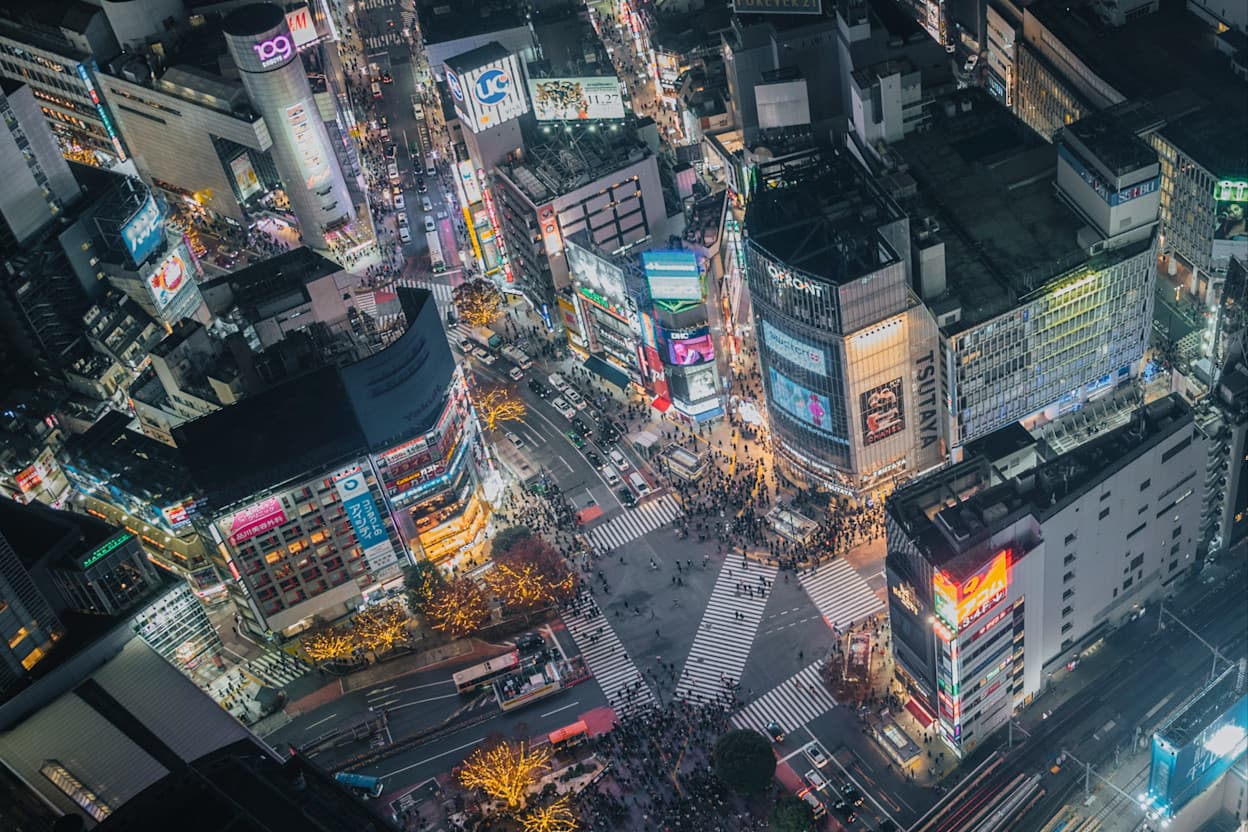 Birds-eye-view of a busy street filled with skyscrapers and neon light signs in Shibuya during the night time.