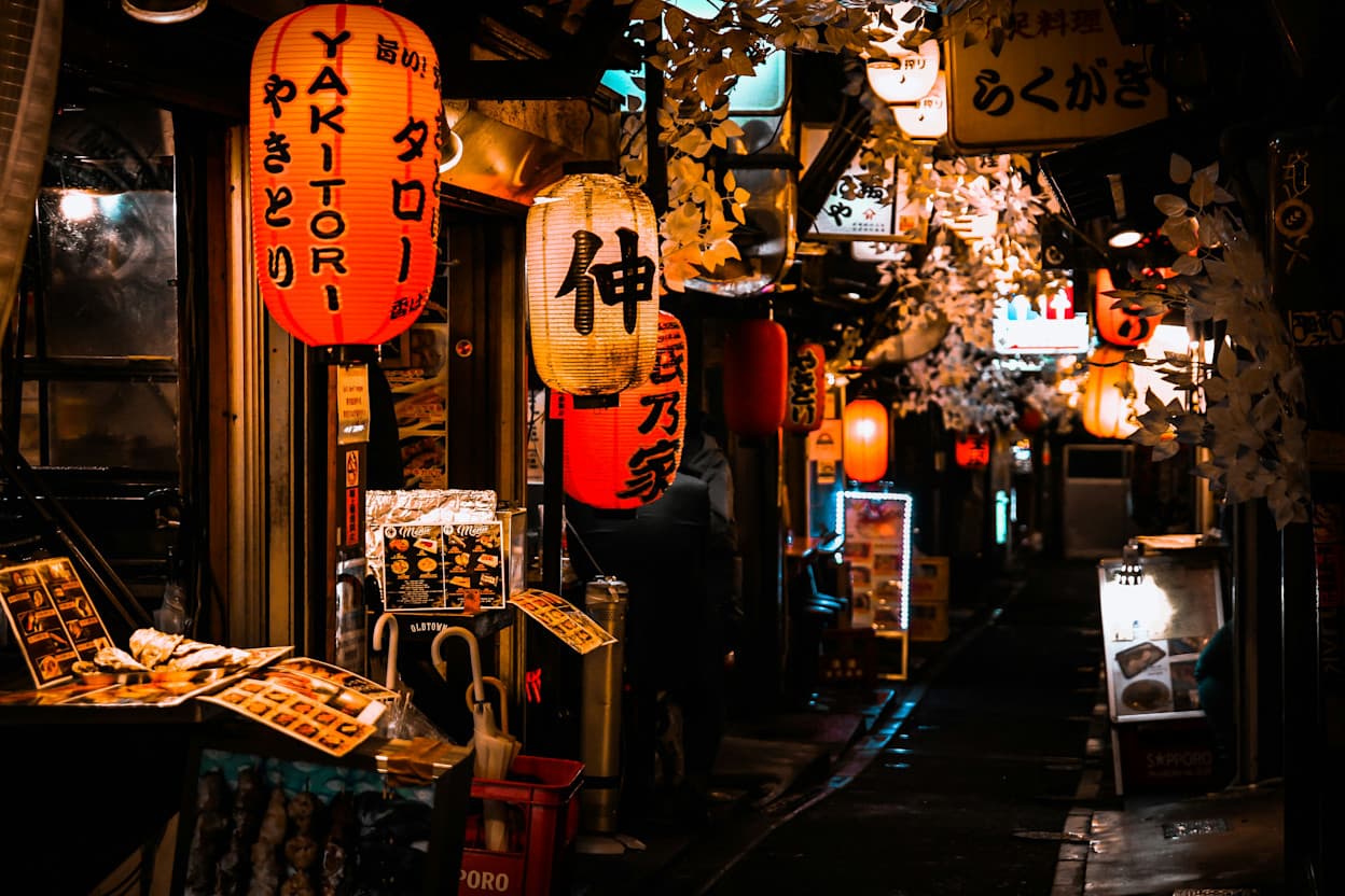 Nighttime in a Shinjuku street filled with Japanese lanterns, lights, and artwork.