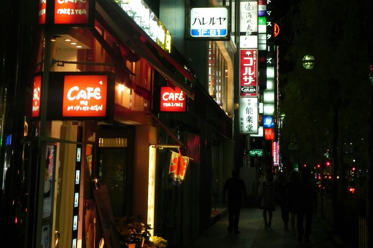 Nighttime on a street in the Tokyo neighborhood, Ginza, filled with bright neon signs with Japanese writing.