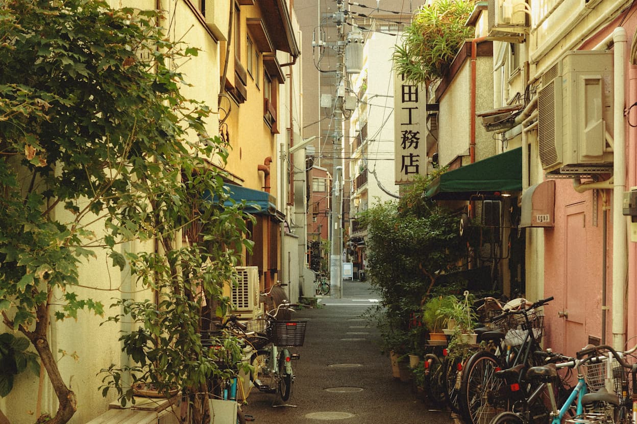 Street with greenery, bikes, restaurants, and residential buildings down a street in the Aoyama neighborhood of Tokyo.
