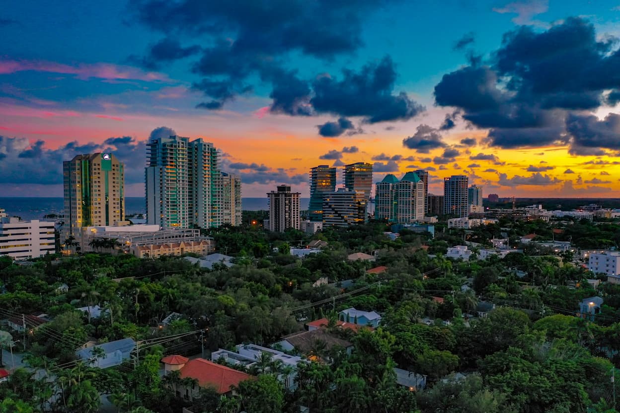 Coconut Grove skyline with high rises and palm trees during sunset.