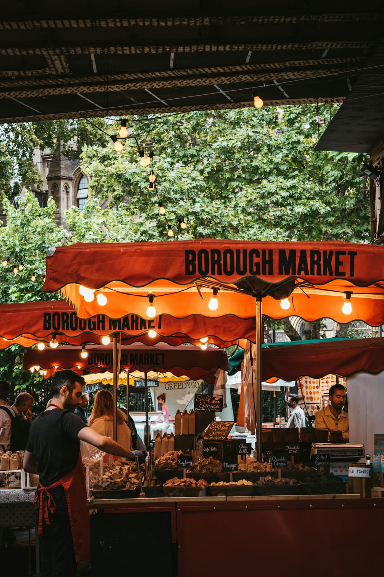 Orange umbrella with lights over food stand in Borough Market, London