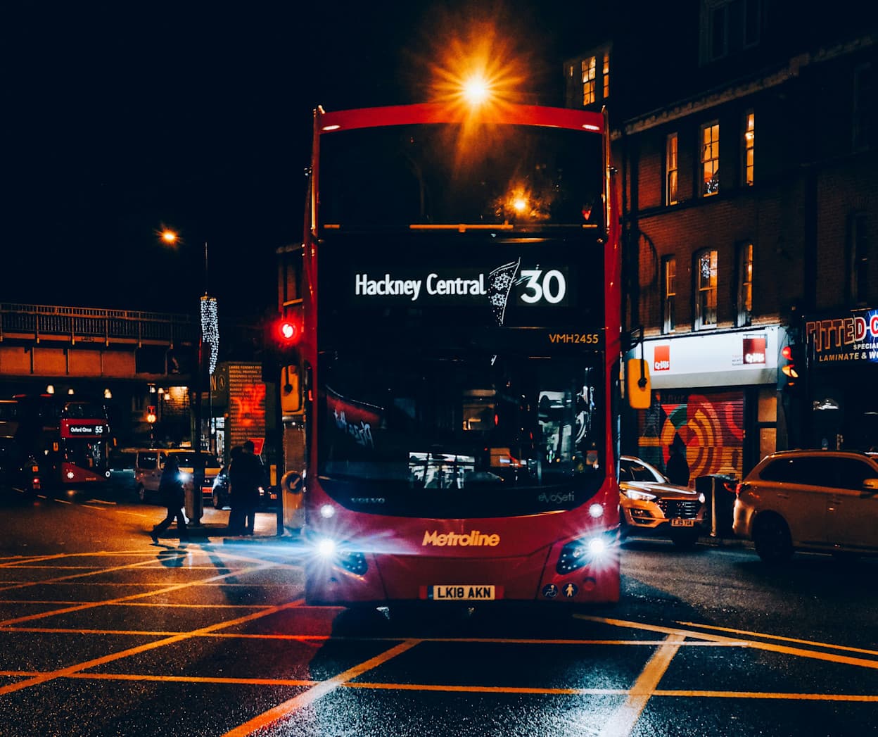Double-decker red bus with "Hackney Central" as the listed destination, driving at night in London