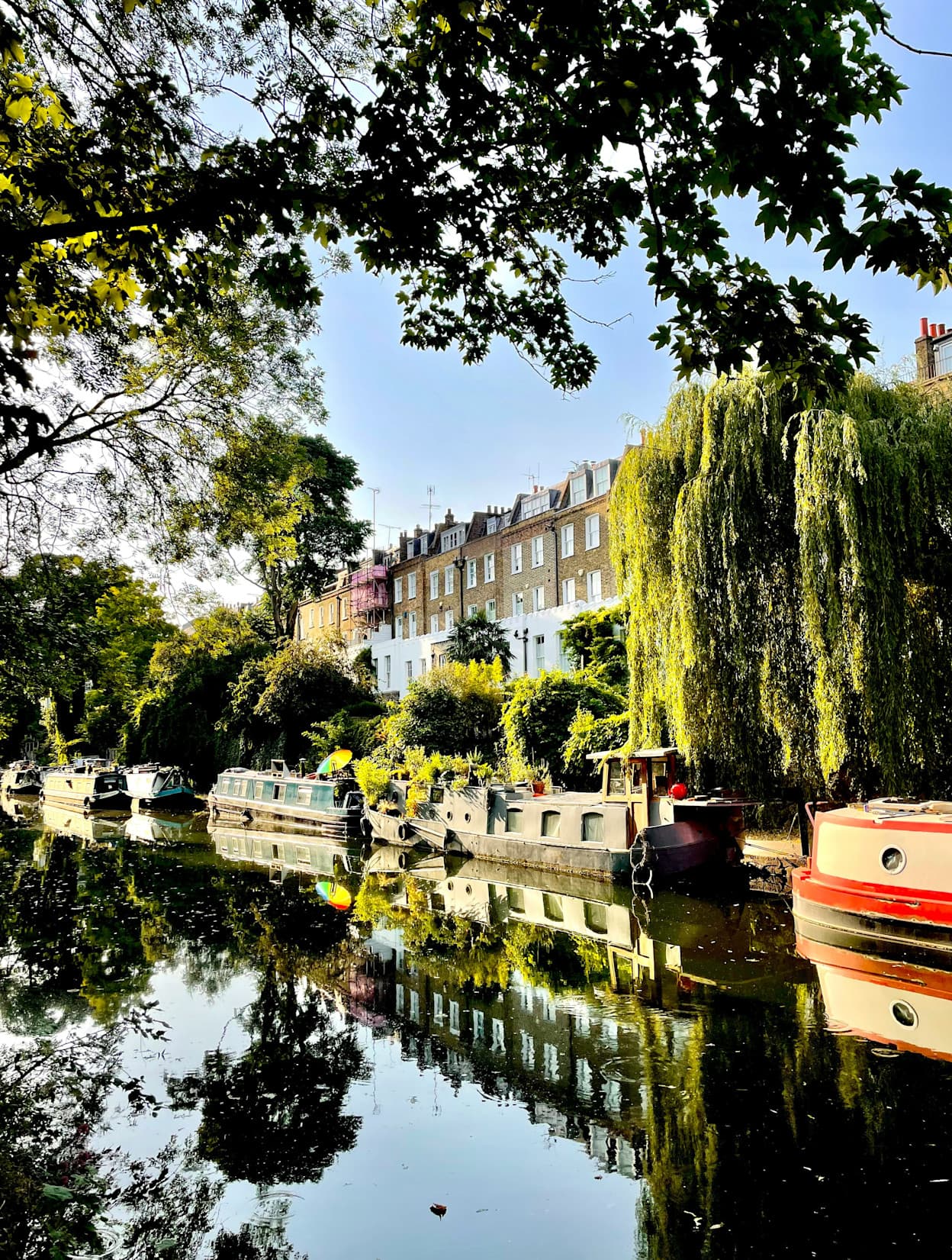 Boats along a the canal in Islington, London with houses and trees in the background