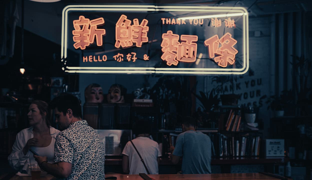 Nighttime photo of a Chinese neon light sign that reads "hello" and "thank you" located at a restaurant inside of New York City's Chelsea market in the Chelsea neighborhoods.