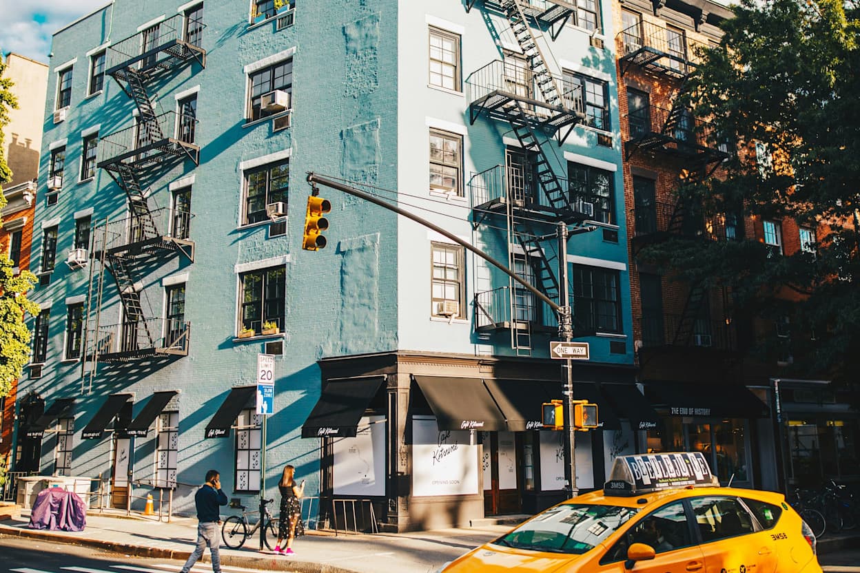 Crosswalk outside of a pale, baby blue building with fire escapes located in the West Village neighborhood of New York Cityu.