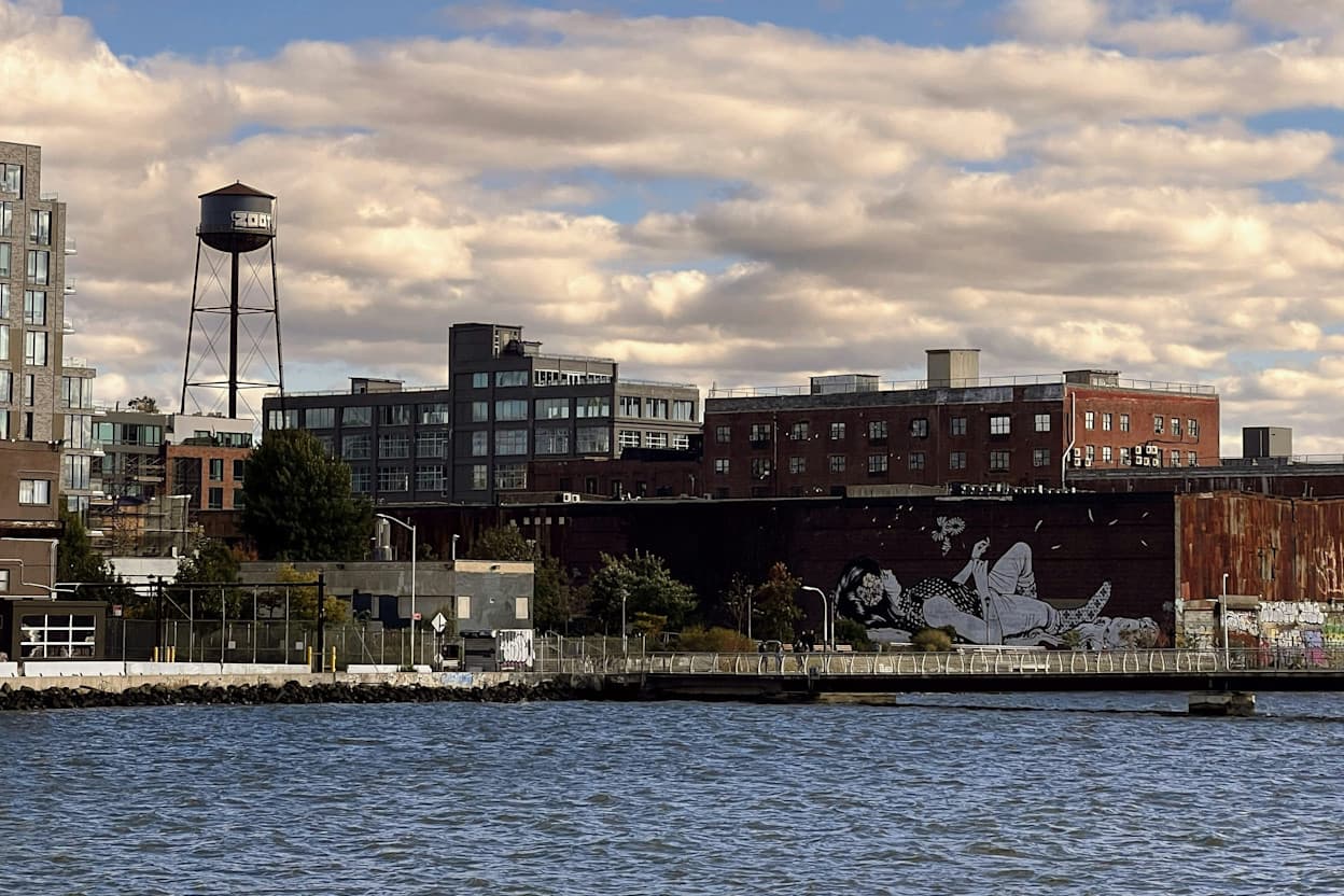View of the East River, water tower, and city buildings from Greenpoint in Brooklyn, New York.