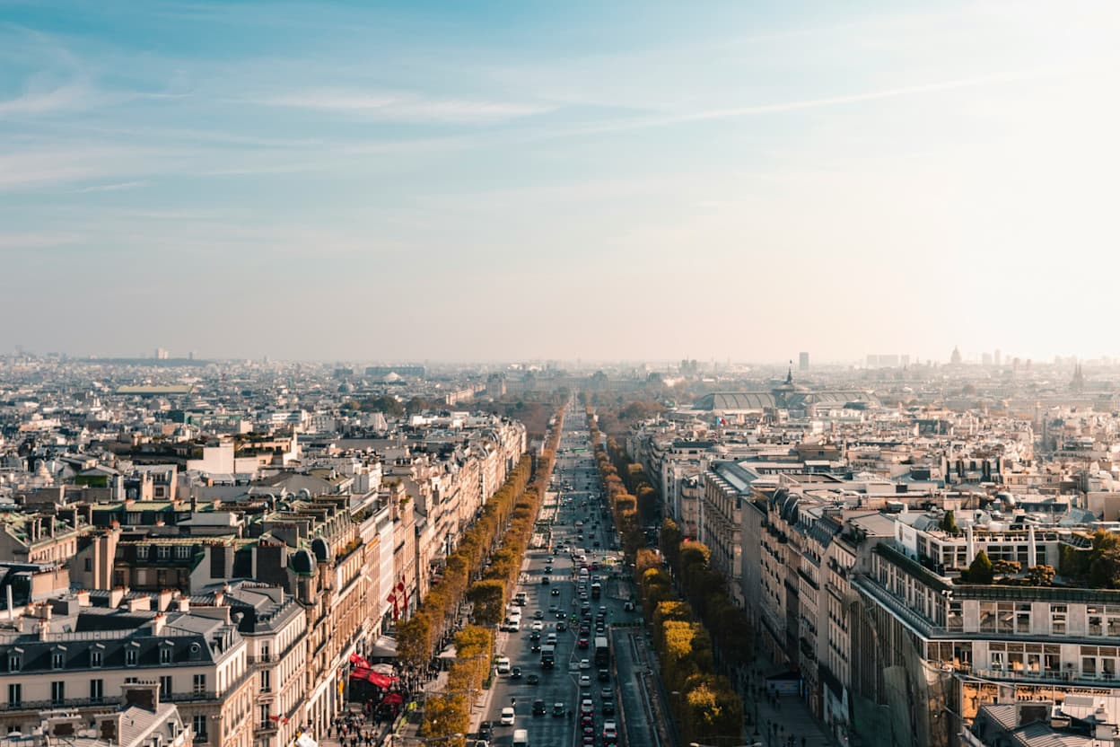 Bird's eye view of the tree-lined street, Champs-Élysées, surrounded by traditional Parisian white buildings with balconies. 