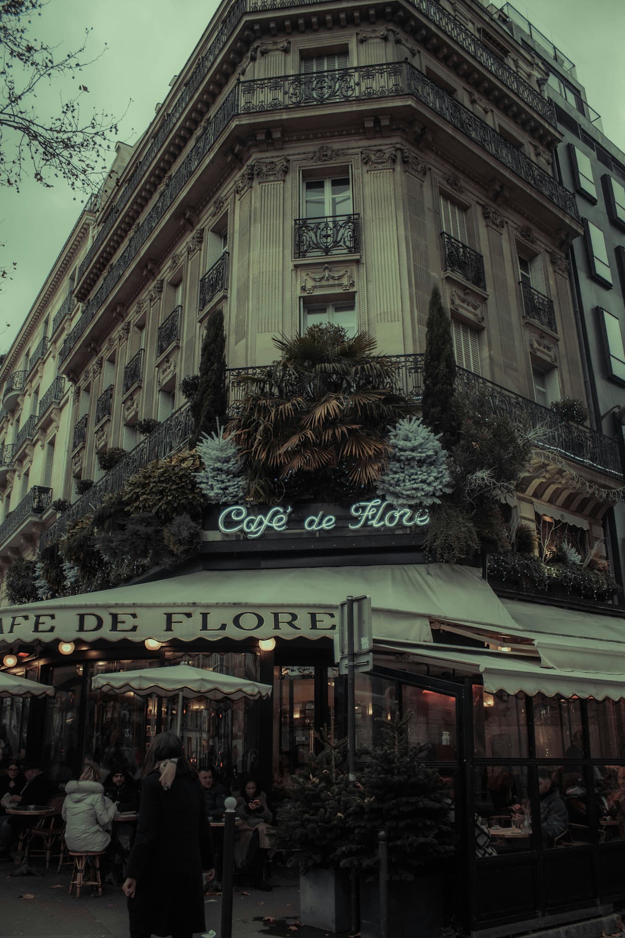 Street view of Cafe de Flore covered in flowers and plants in the Saint-Germain-des-Prés neighborhood of Paris