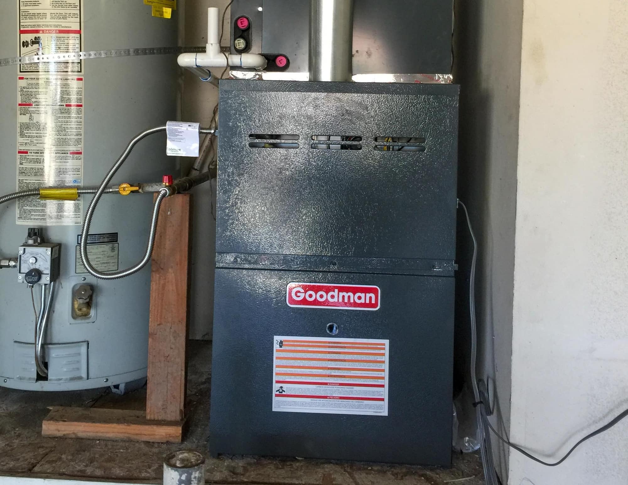 Goodman HVAC unit installed next to a water heater in a utility room.