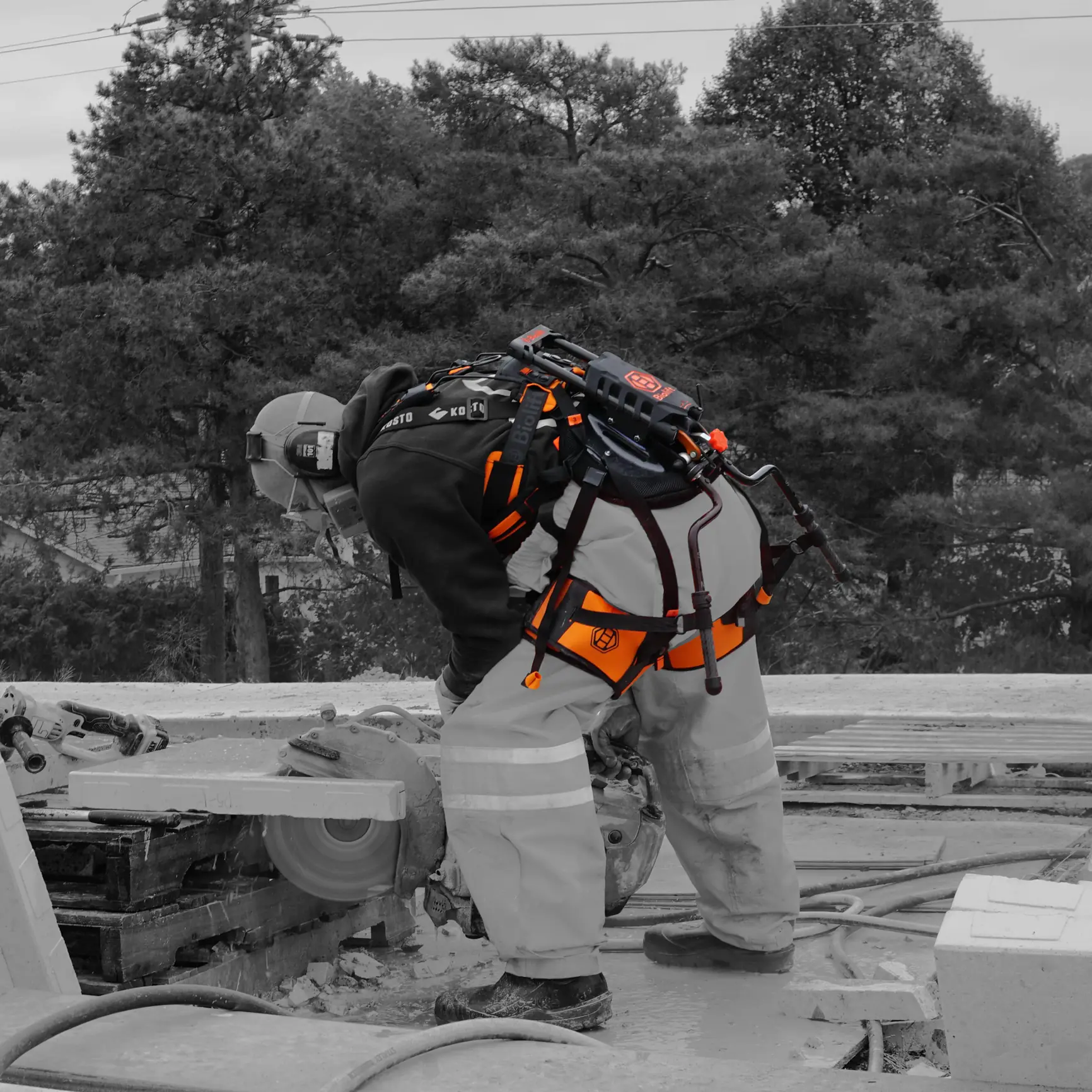 Worker cutting a slab with a cut-off saw, wearing the Biolift Carbon exoskeleton