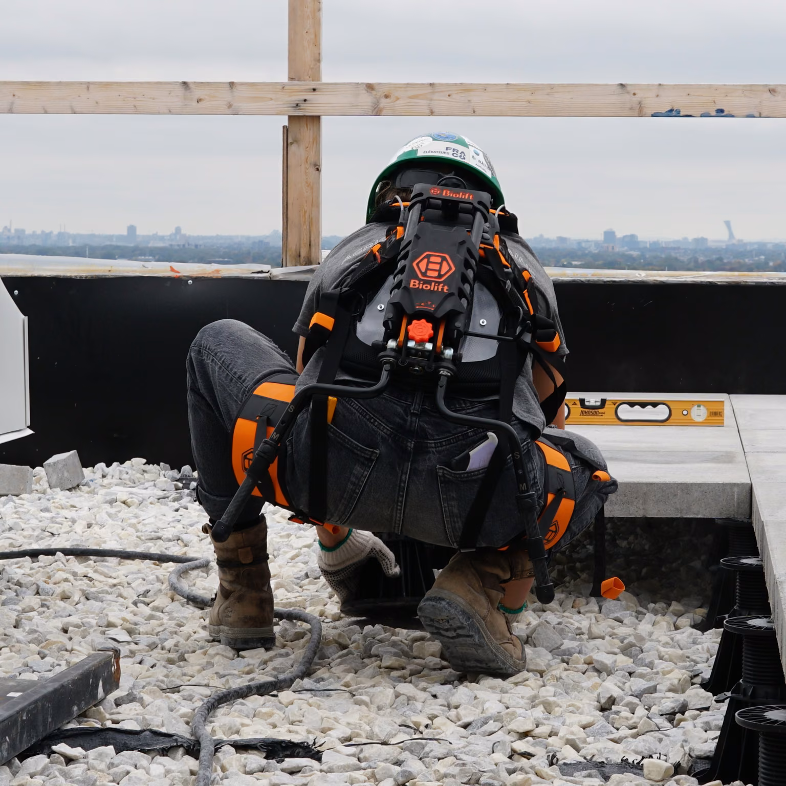 Worker crouching on a rooftop with the Biolift Carbon exoskeleton