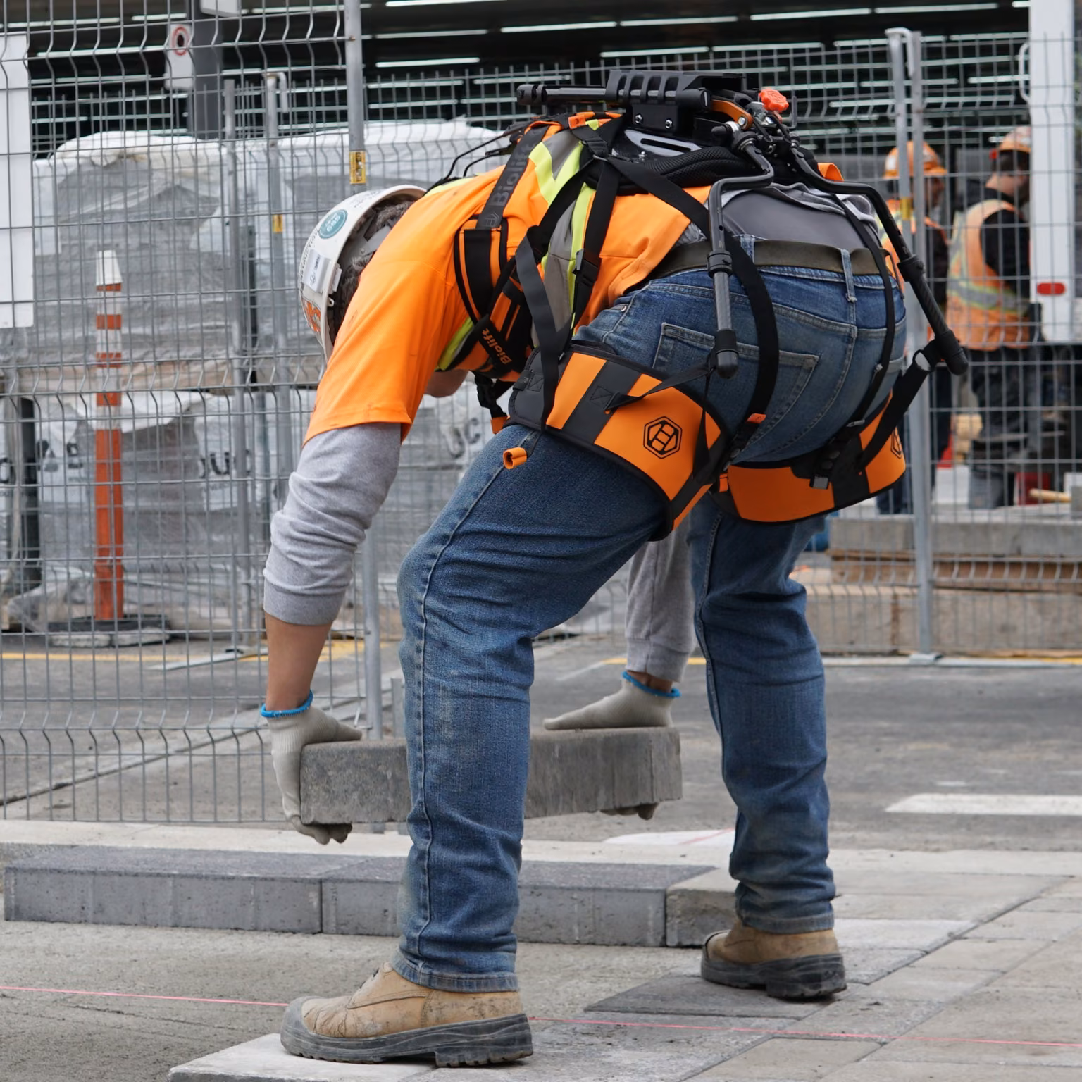 Worker bending to pick up a paver with the Biolift Carbon exoskeleton