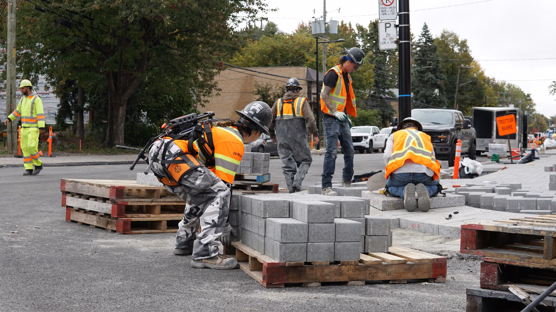Paving crew on a city street, one worker lifting pavers with the Biolift Carbon exoskeleton