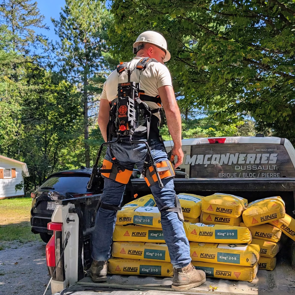 Maçon dans la boîte de son camion avec l'exosquelette Biolift Carbon