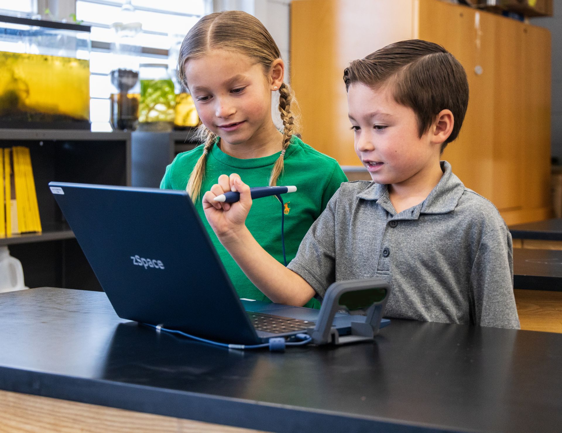 boy an dgirl are controlling a stylus to virtually move objects on a 3D screen