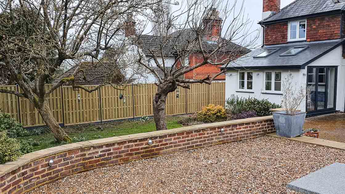 Closeboard timber fence with Green Leaves Fencing & Gates sign installed on a slope in East Grinstead.