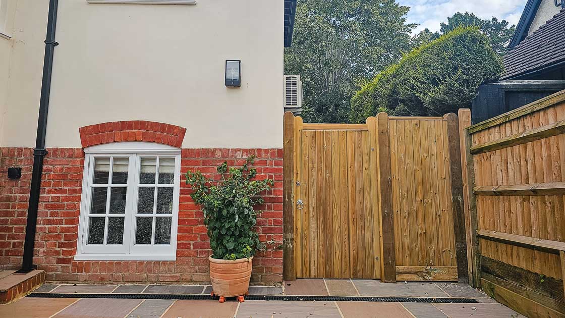 Double timber entrance gates with curved tops and metal fittings, crafted by Green Leaves Fencing & Gates, West Sussex.