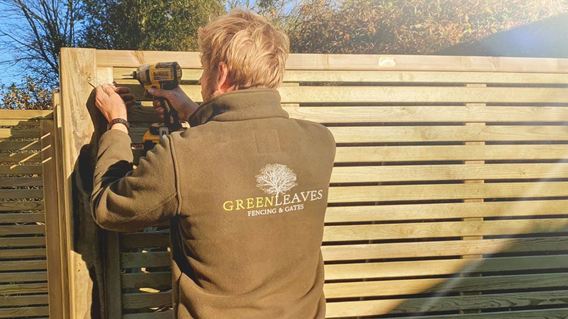 Green Leaves Fencing and Gates installer fixing a timber fence panel in a customer’s garden in East Grinstead.