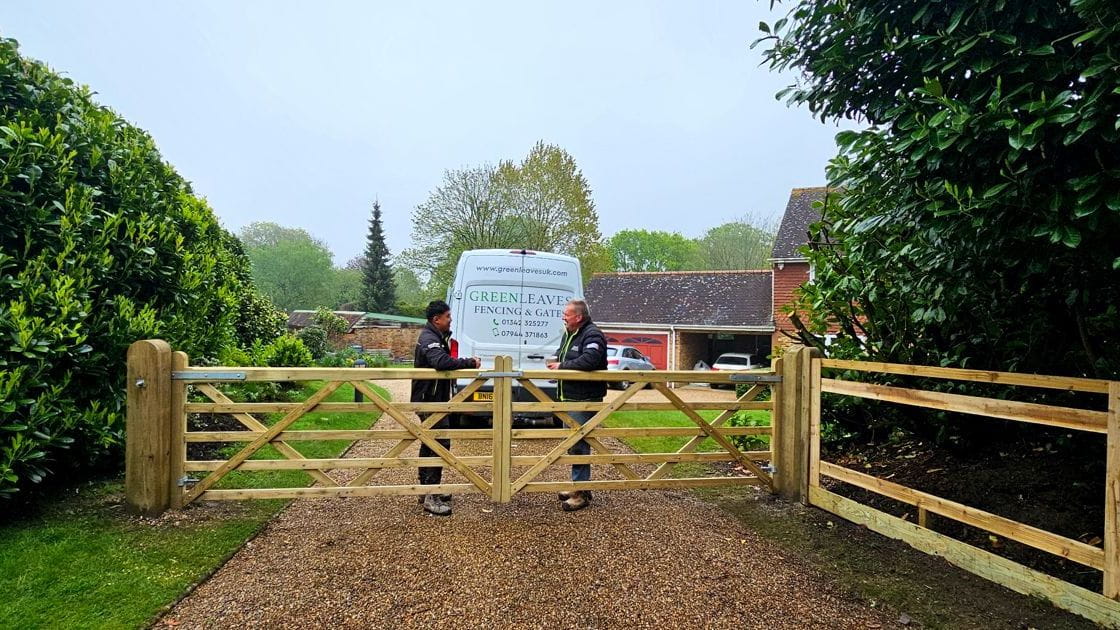 Closeboard timber fence with Green Leaves Fencing & Gates sign installed on a slope in East Grinstead.