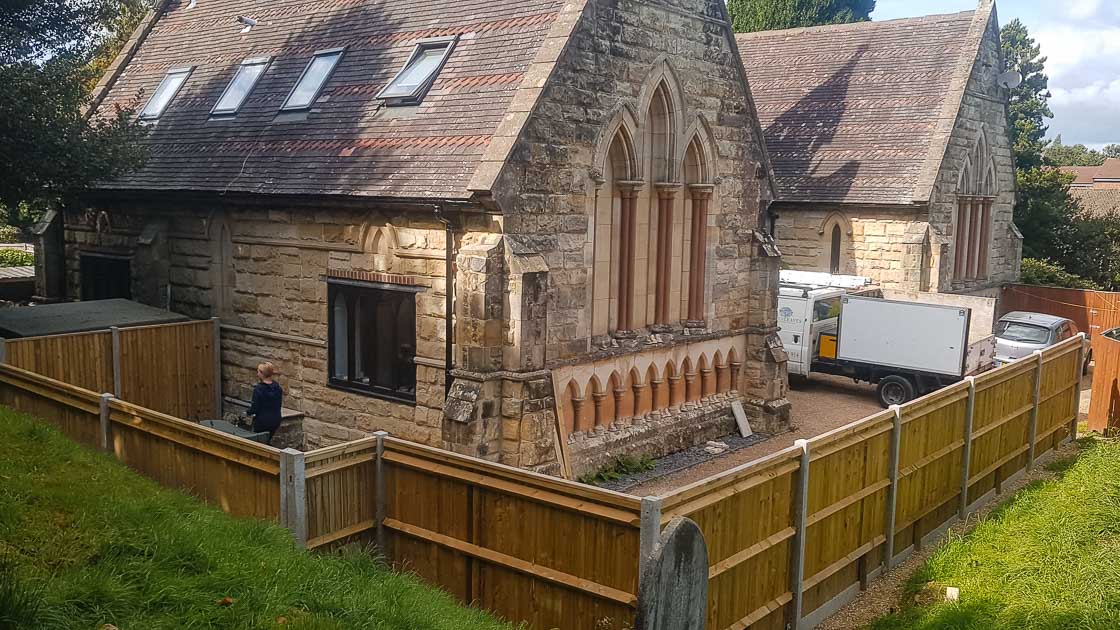 Closeboard timber fence with Green Leaves Fencing & Gates sign installed on a slope in East Grinstead.