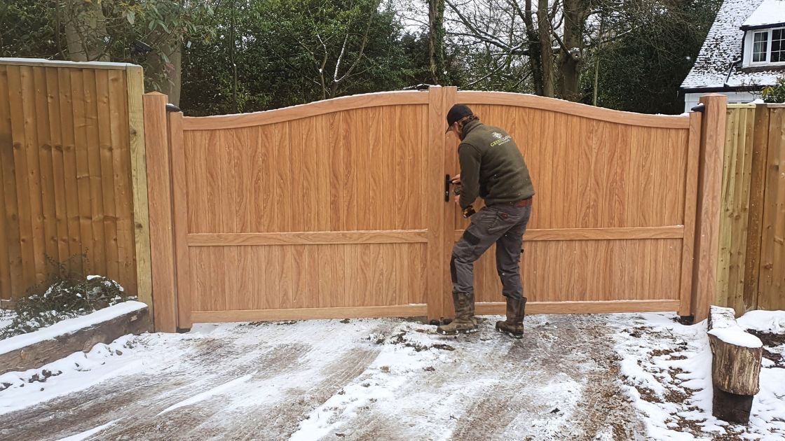 Closeboard timber fence with Green Leaves Fencing & Gates sign installed on a slope in East Grinstead.