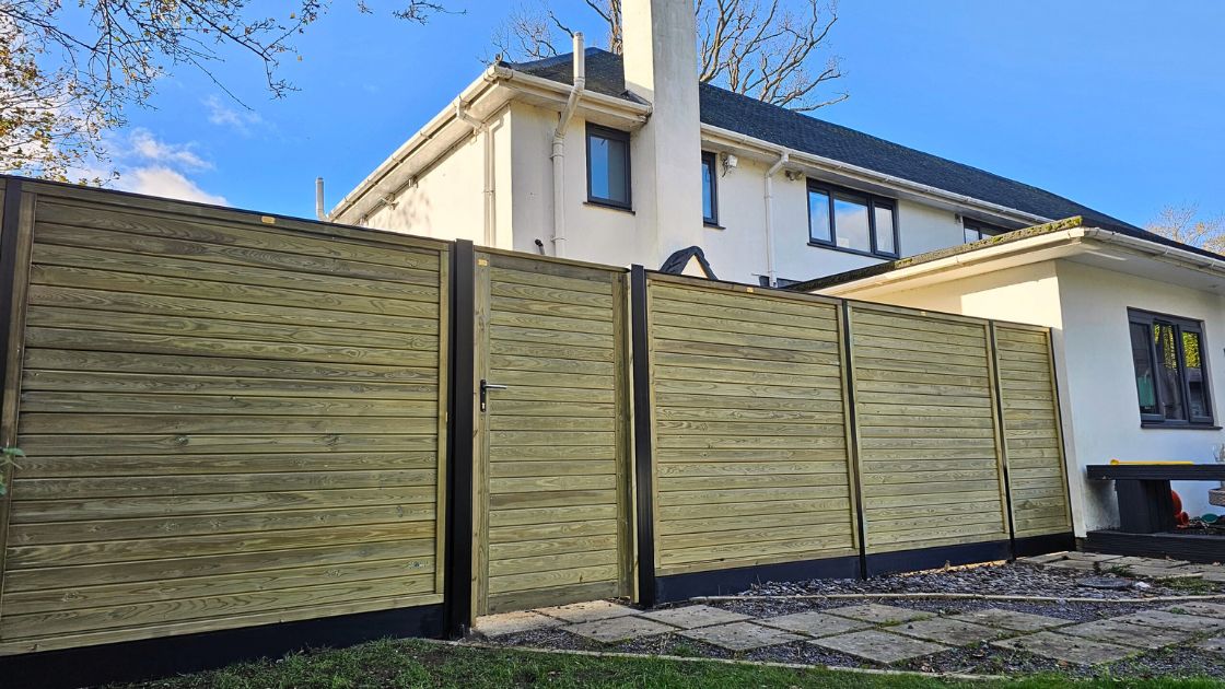 Closeboard timber fence with Green Leaves Fencing & Gates sign installed on a slope in East Grinstead.