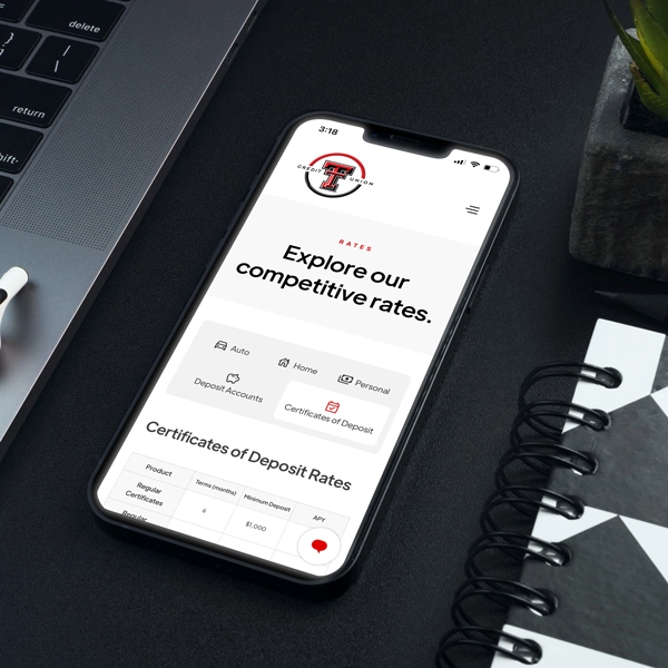 Mobile phone on desk displaying Texas Tech Credit Union's rates page