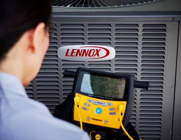 Technician using yellow diagnostic tool on a Lennox HVAC unit.