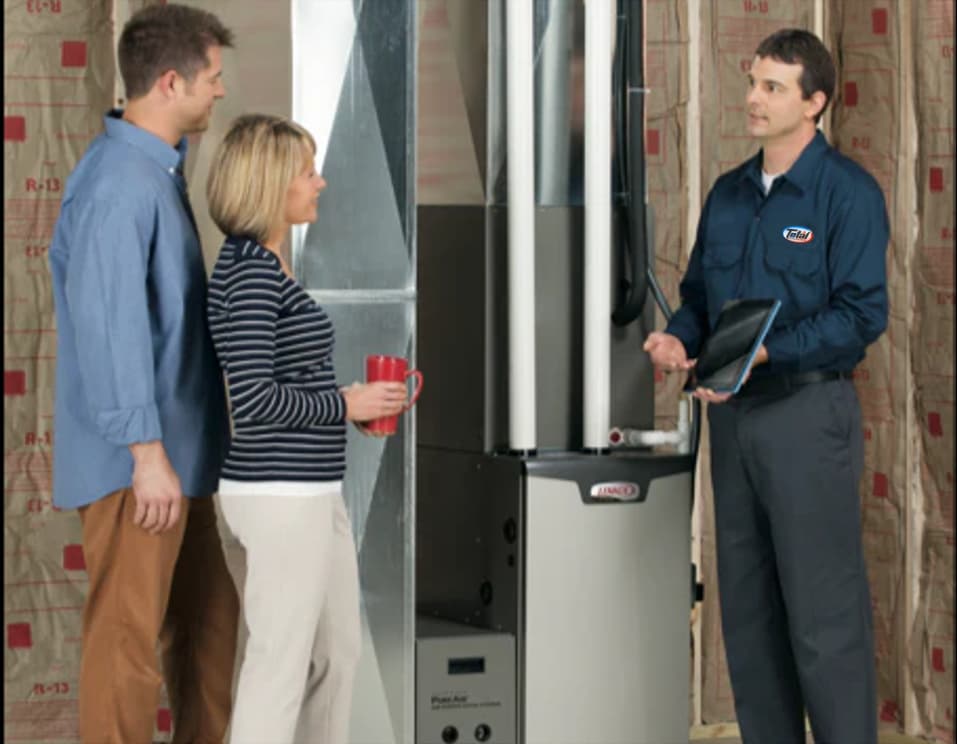 Technician in uniform explaining a furnace system to a couple.