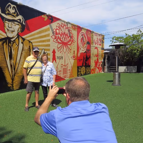 Coppia sorridente in posa davanti al murale di Shepard Fairey a Wynwood Walls