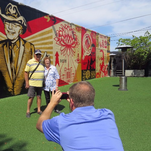 Coppia sorridente in posa davanti al murale di Shepard Fairey a Wynwood Walls