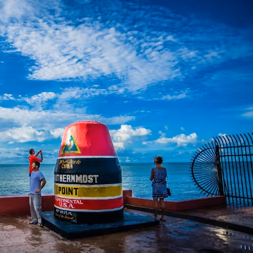 Visitatori che creano ricordi al Southernmost Point Monument sotto un cielo azzurro a Key West