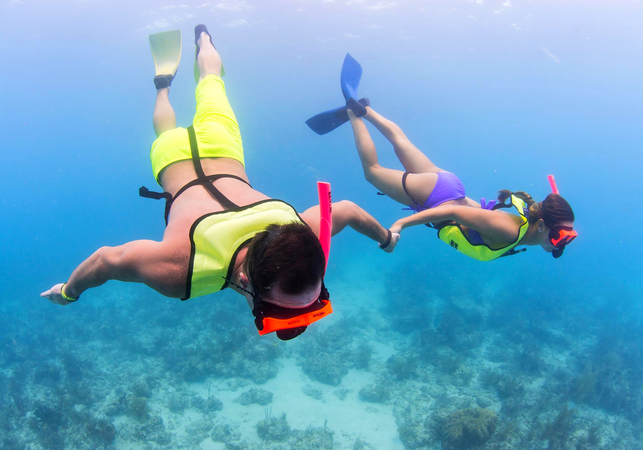 Lovers snorkeling and holding hands under water