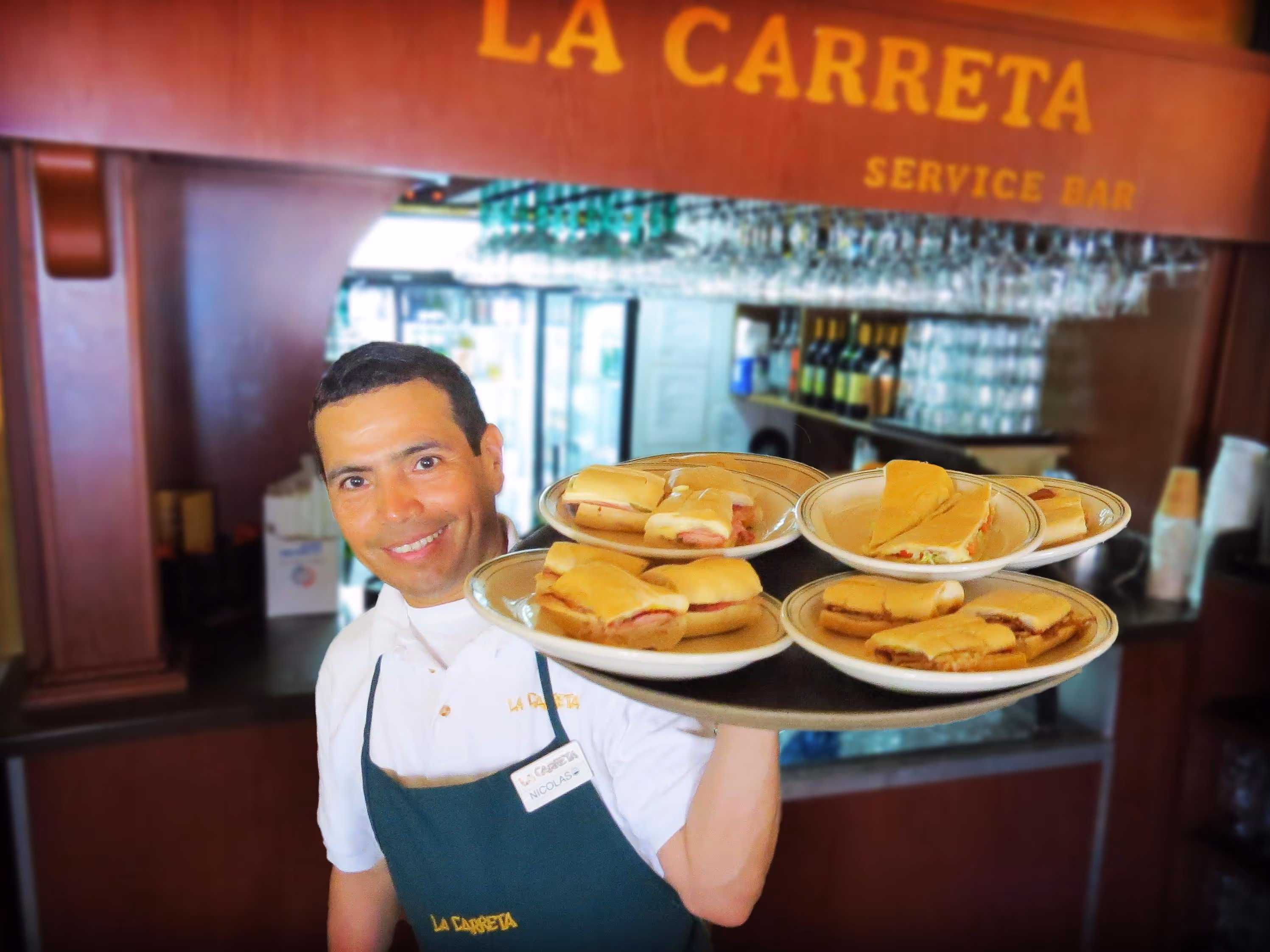 Smiling waiter holding a tray of food at La Carreta restaurant