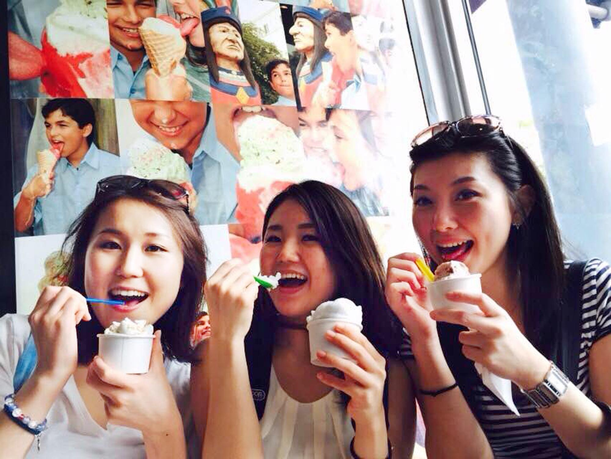 Three smiling ladies eat ice cream inside the parlor
