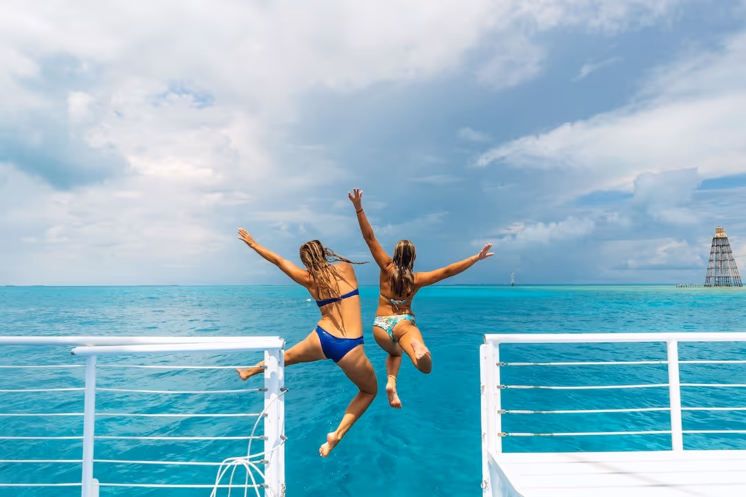 Joyful friends jumping off the boat