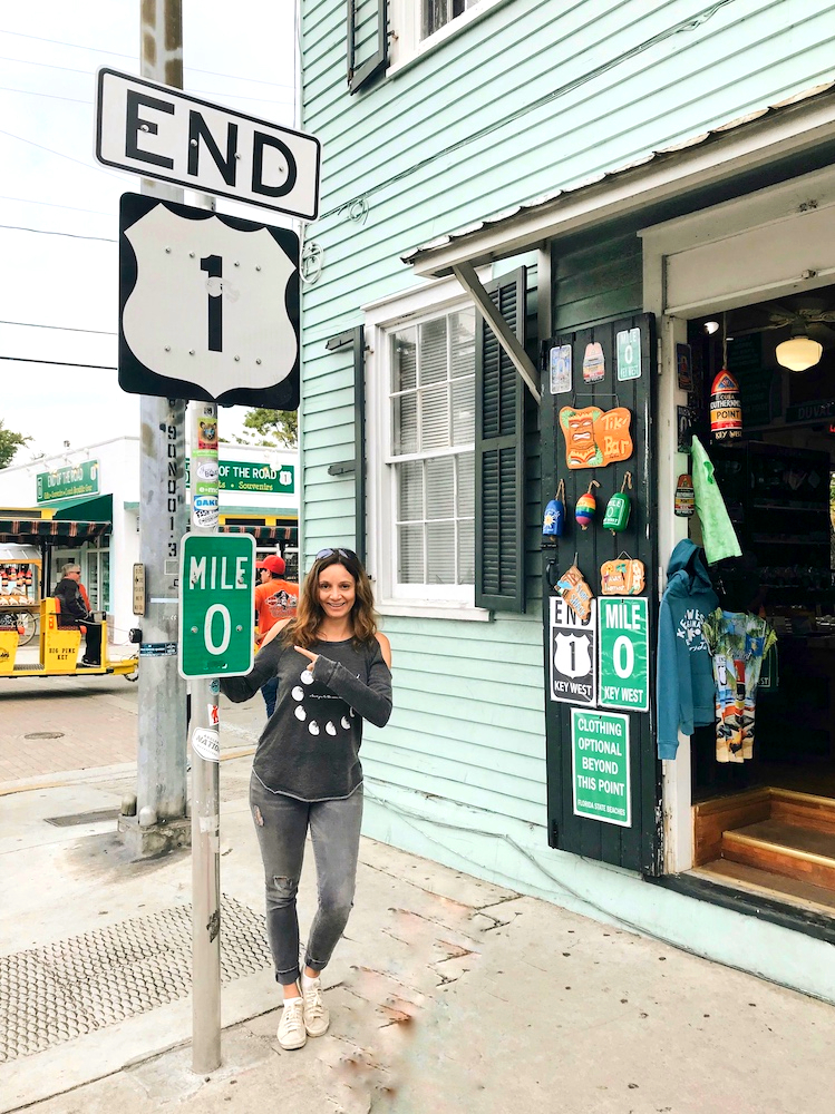 Young lady standing next to Mile Marker 0