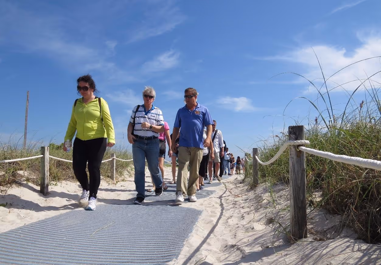 Tour guide and older couple walking back from the bach, under blue skies