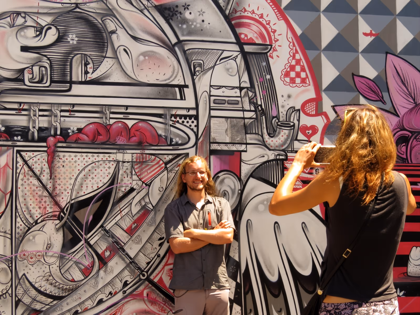 Young man posing for his wife in from of a steampunk-themed mural