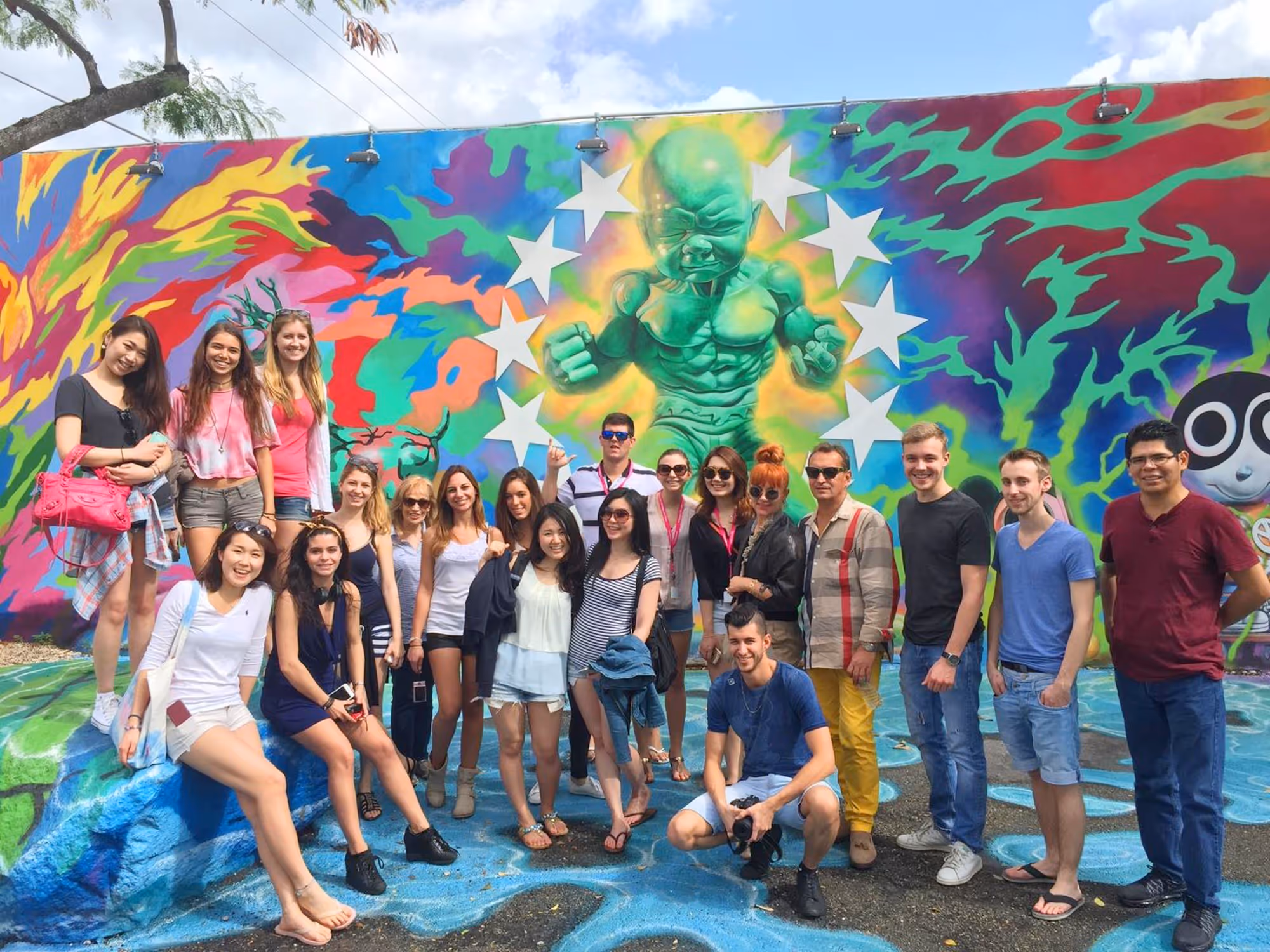 Group of college students posing near the Baby Hulk mural , under blue skies