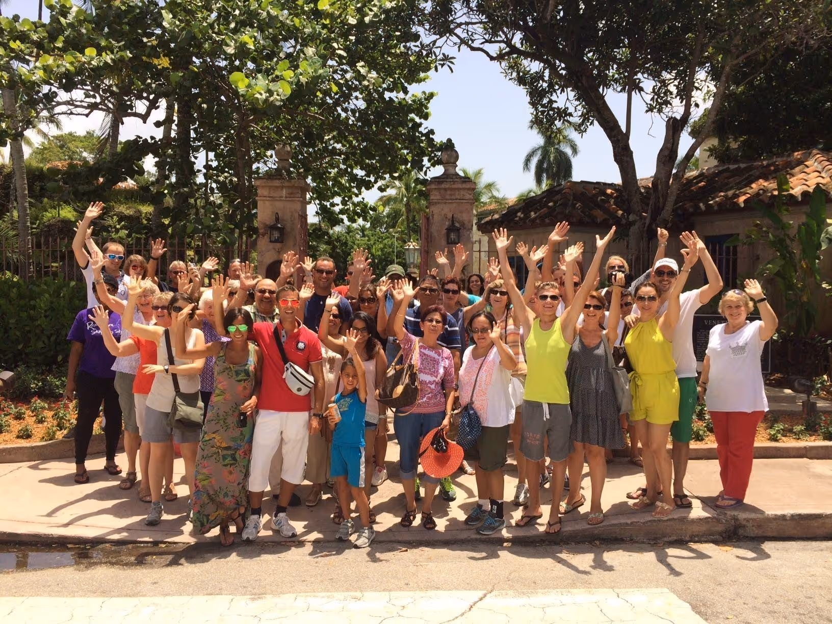 Group of smiling people posing with their arms in the air, under sunny skies