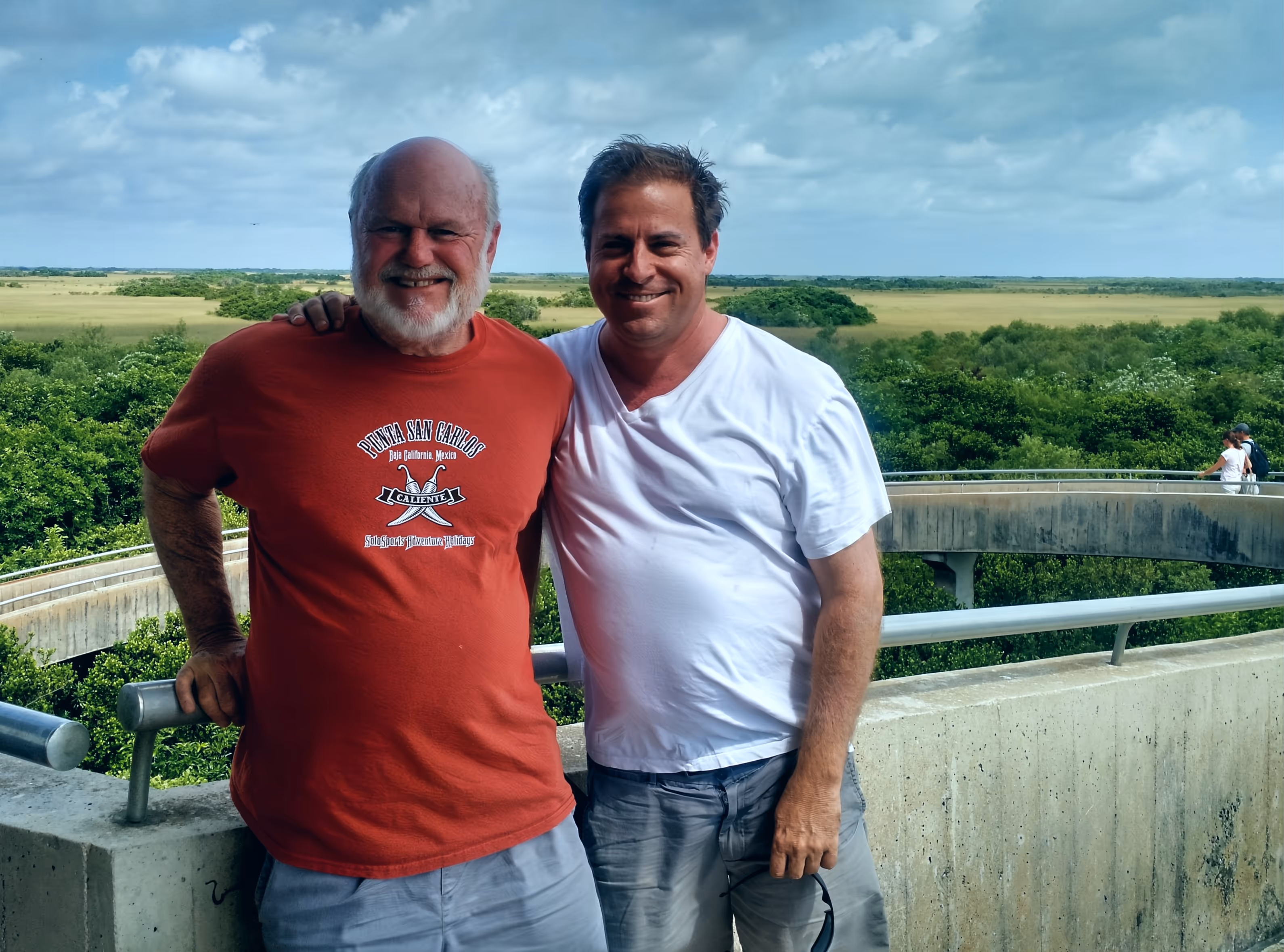 Dad and son with arms around each other under sunny skies in the Everglades