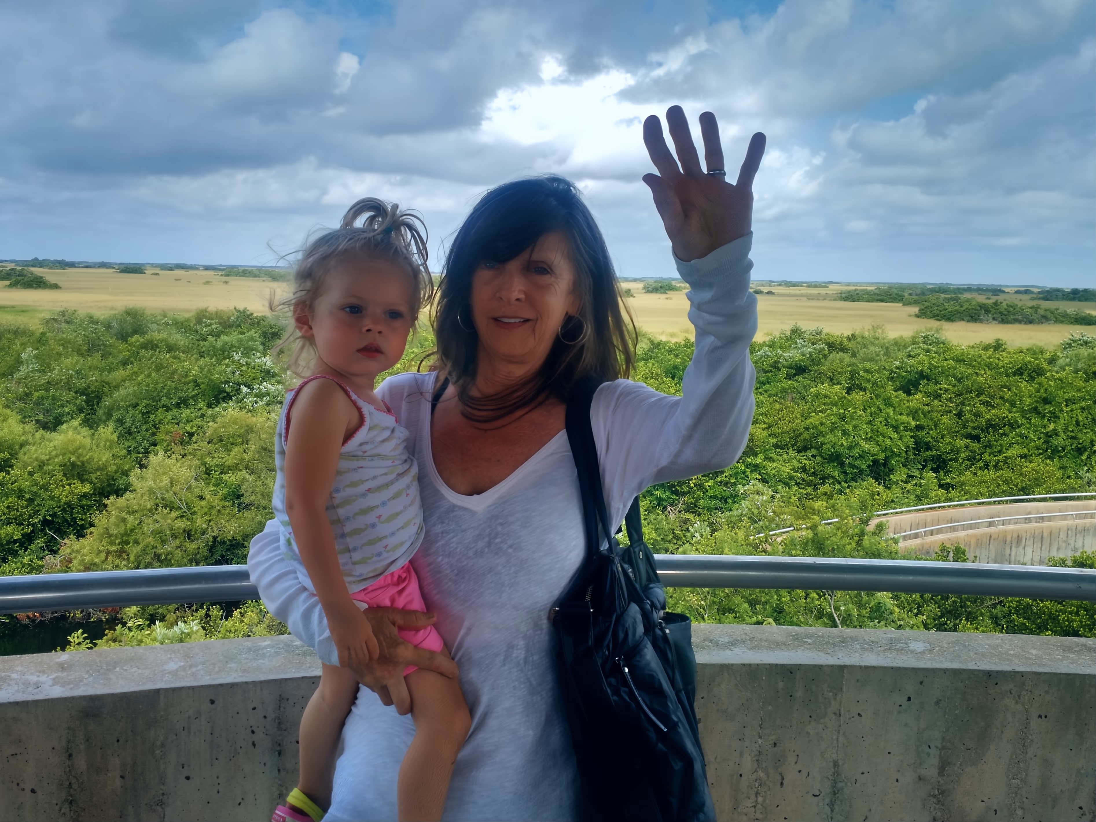 Grandmother and granddaughter waving hello with a beautiful view of the Everglades in the background